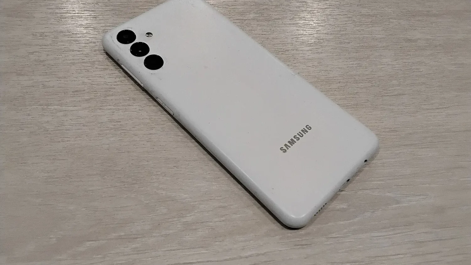 Белый смартфон Samsung с тремя камерами, вид сзади