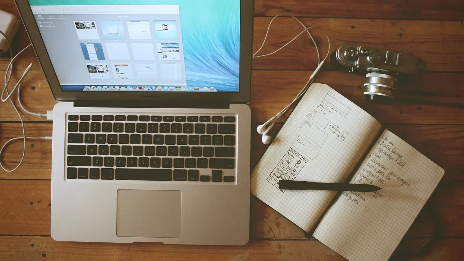 Ноутбук MacBook и открытый блокнот на деревянном столе