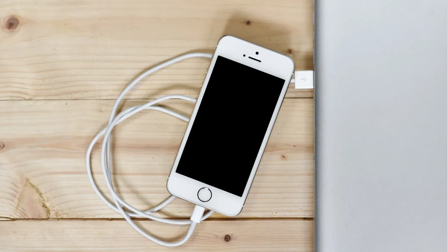 iPhone на зарядке лежит на деревянном столе