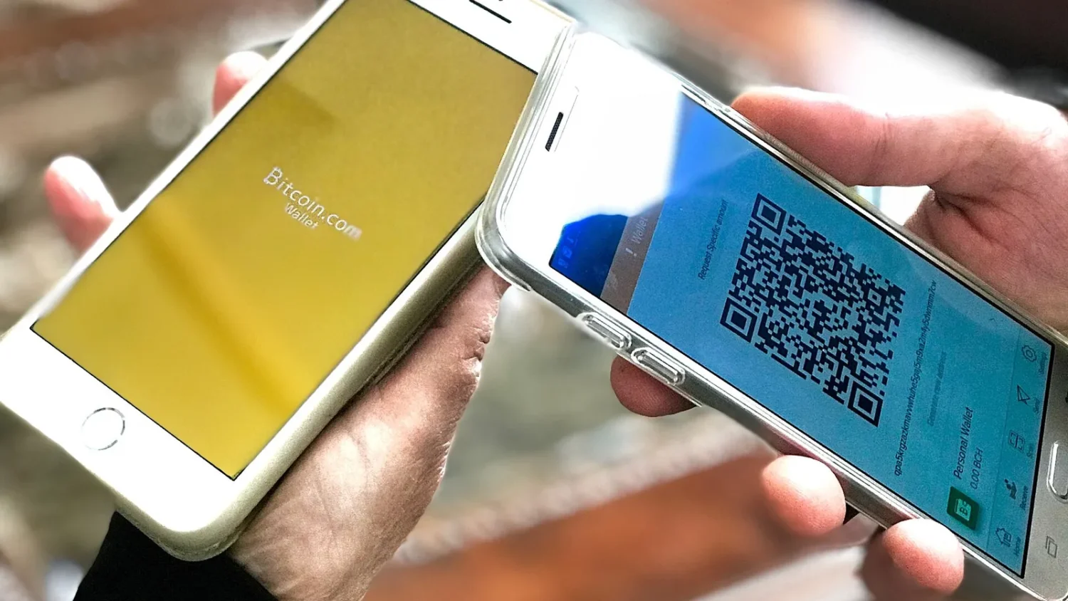 Два смартфона в руках, на экране одного QR-код