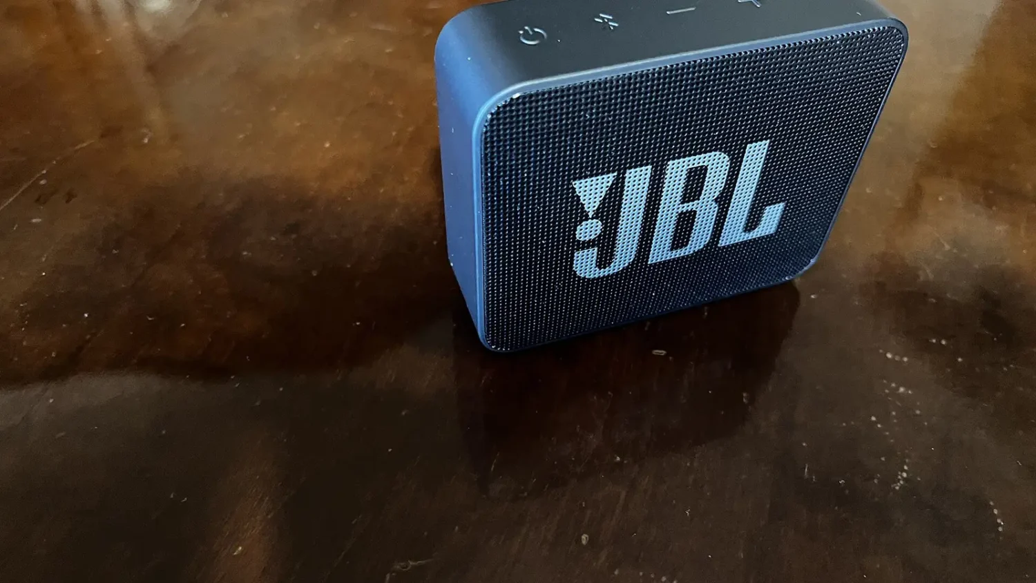 Синяя портативная колонка JBL на деревянном столе