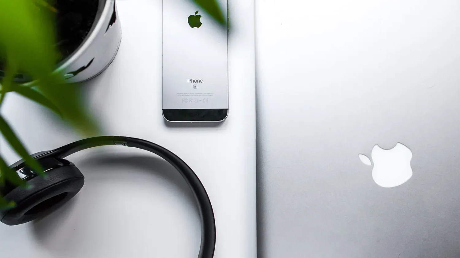 Серебристый iPhone и наушники на белом столе