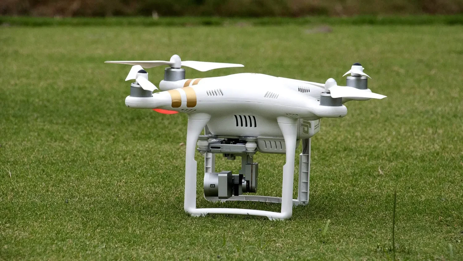 Белый квадрокоптер DJI Phantom на зелёной траве