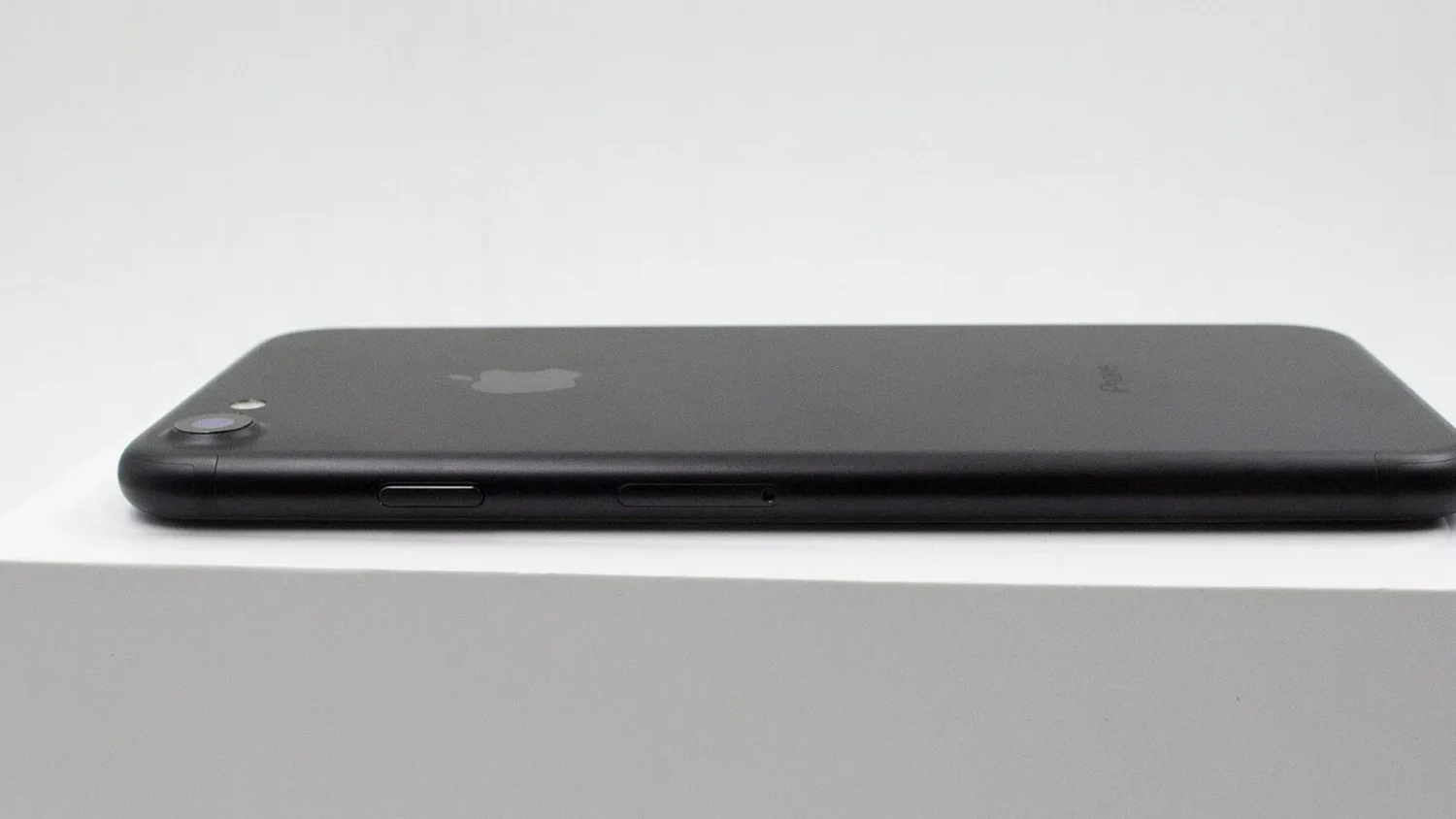 Чёрный iPhone на белом фоне, вид сбоку