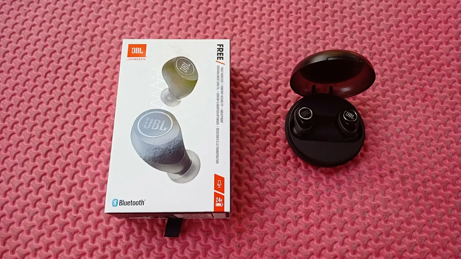 Беспроводные наушники JBL и коробка на розовом фоне