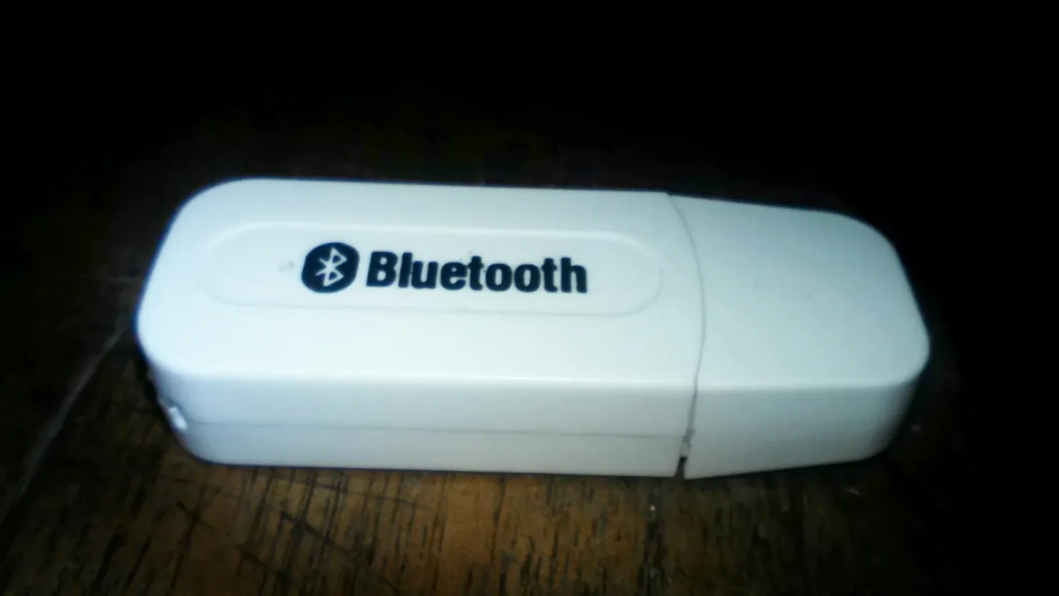 Белый Bluetooth-адаптер на чёрном фоне