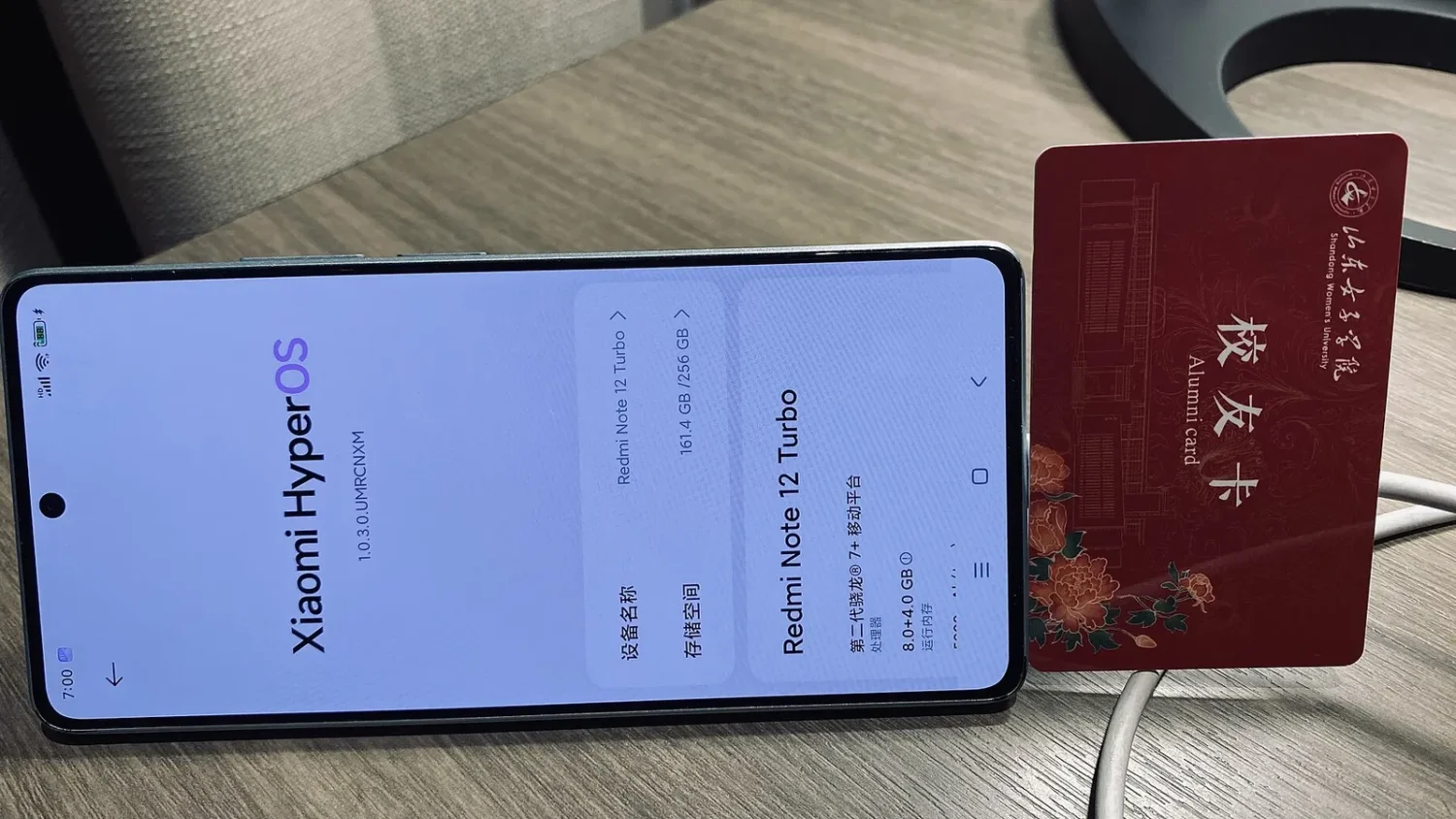 Смартфон Xiaomi с экраном HyperOS в руке рядом с упаковкой